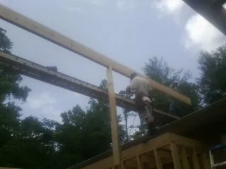 Carpenter setting a ridge beam over a new addition frame — Ice Dam Removal by Roofing Brothers in Elkview