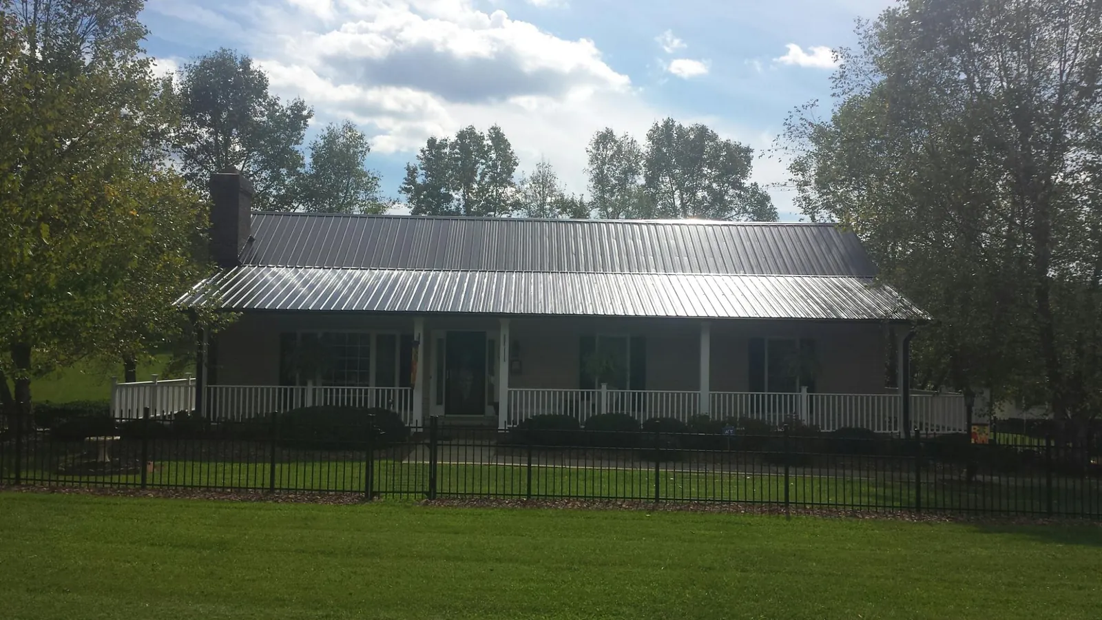 Gray metal roof on a brick ranch with a full width front porch — Gutter Guard Installation work by our crew in Elkview
