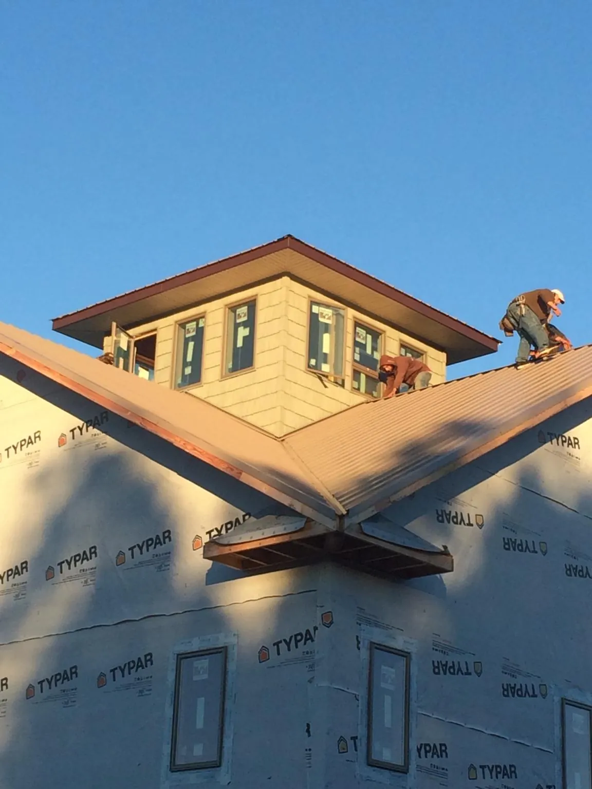 Roofers working around a rooftop cupola on a new metal roof at sunset — Roof Waterproofing in Elkview by Roofing Brothers